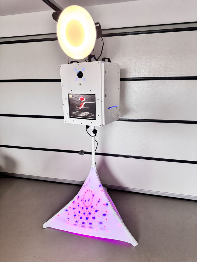 Fotobox mit bunter LED-Beleuchtung, vor einer Wand präsentiert.